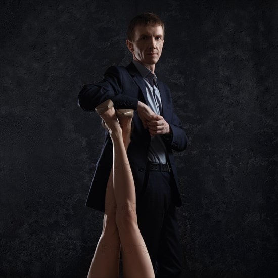 Middle age man in suit leans on female legs in stilettos lifted up