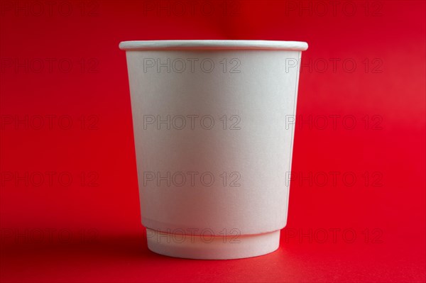 Cardboard cup without lid on red background