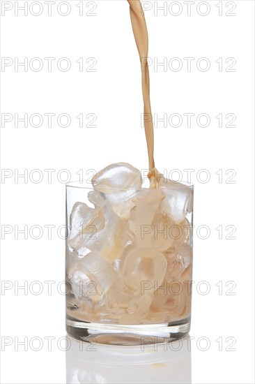 Irish creme liqueur pouring in a glass full of ice