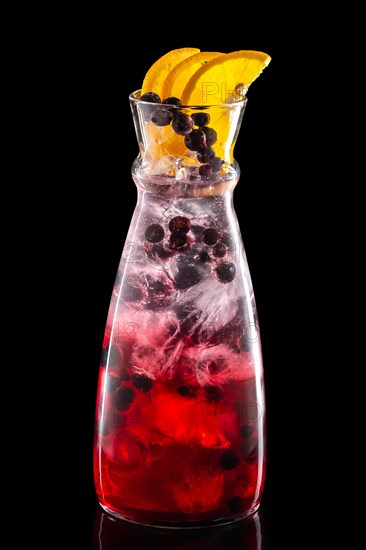 Pitcher with black currant and orange ice lemonade isolated on black background