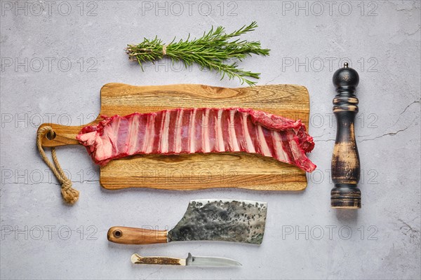 Overhead view of raw fresh deer ribs with spice and herb over concrete background