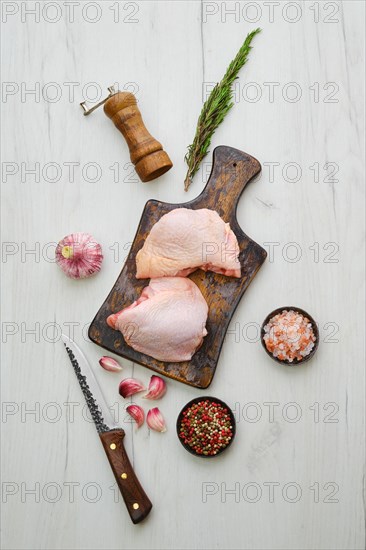 Raw chicken thighs on wooden cutting board ready for cooking