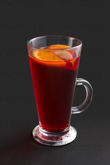 Hot cherry tea with orange and lemon on gray background