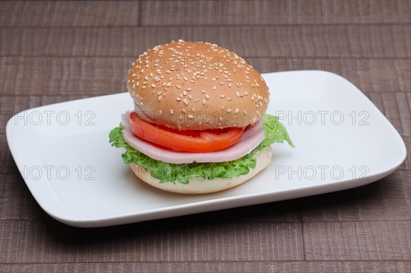 Fresh tasty burger on plate on wooden table