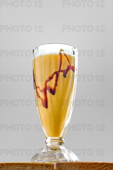 Low angle view of glass of banana smoothie on wooden table