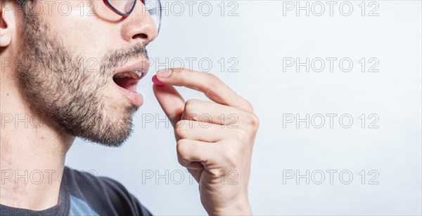 Man putting a pill in his mouth isolated. Close-up of a man taking an aspirin. Person taking a pill isolated