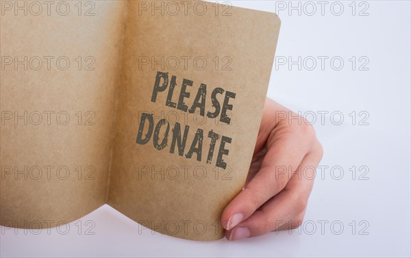 Hand holding a sheet of paper with please donate wording