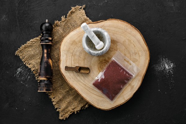 Wooden cross section with sumac in plastic package and stone mortar and mill