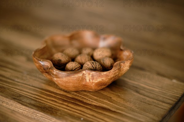 Wooden bowl of unleeled walnuts on the table