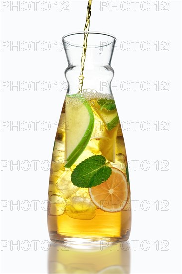 Filling up the jar with icy apple and orange drink with mint flavour