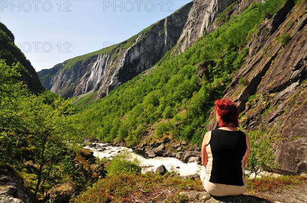 Woman sitting in a rock gorge with waterfall in Norway