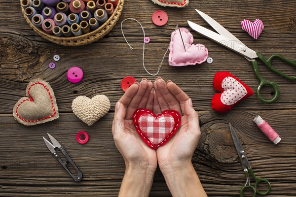 Hands holding a red heart shape on wooden background