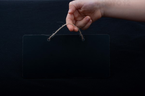 Rectangular shaped black notice board in hand on black background