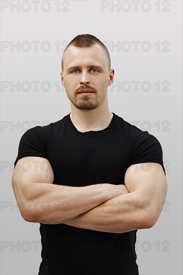 Portrait of strong man in black t-shirt with crossed arms