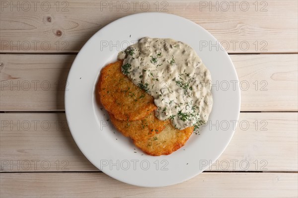 Traditional belorussian potato pancakes draniki with mushroom sauce on a plate