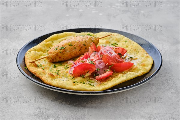 Kebab served on tortilla with tomato and red onion