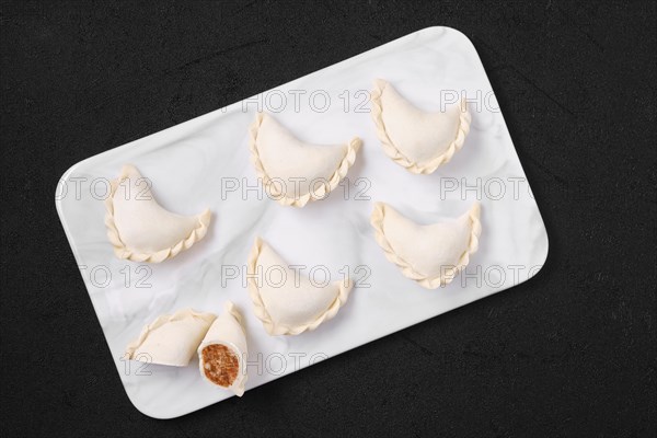 Top view of frozen dumplings stuffed with beef meat and provencal herbs on marble serving plate
