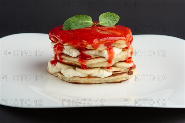 Pile of flapjacks with strawberry jam and banana