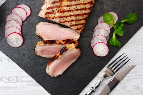 Sliced grilled pork fillet with fresh tomatoes and raddish served with glass of red wine