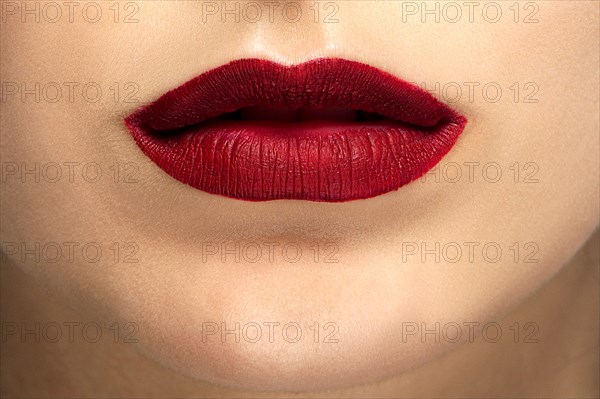 Close up photo of female face with tan makeup and red mat lips
