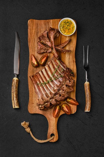 Overhead view of grilled ribs of lamb on a plate with spicy sauce