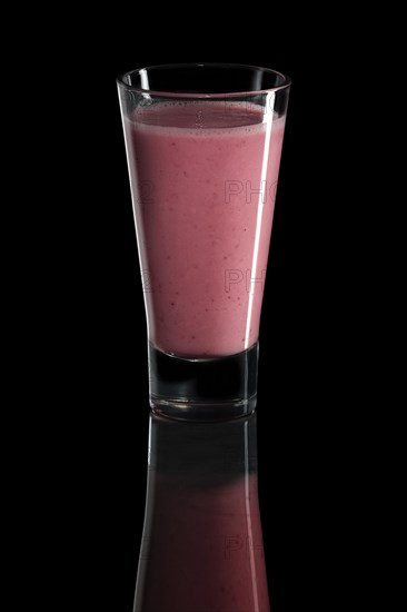 Glass of raspberry and strawberry cocktail isolated on black