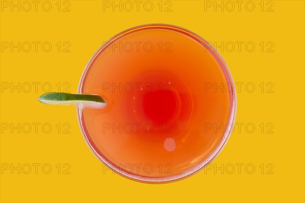 Top view of cosmopolitan cocktail on yellow background