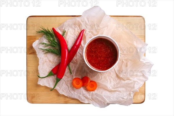 Top view of plate with hot and spicy soup with chilli pepper and carrot isolated on white