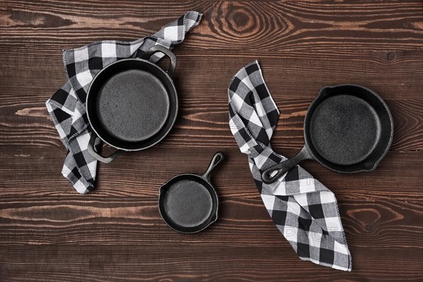 Three empty mini cast-iron skillets on wooden table