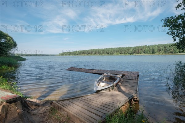 Old metal boat near pier in forest lake