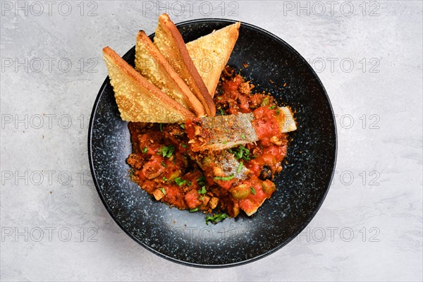 Top view of fried zander served with steamed tomato