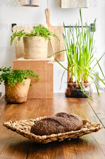 Brown bread with sesame in wicker bowl on a kitchen table