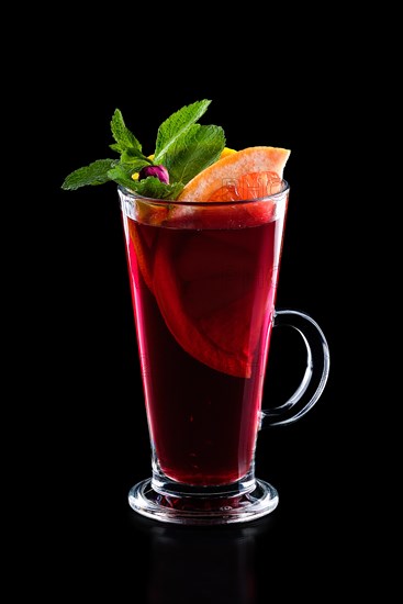 Glass of hot rose tea with grapefruit and mint isoalted on black.