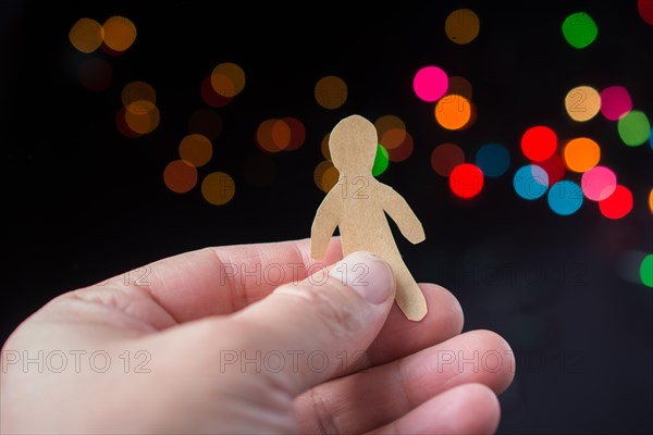 Paper man shape in hand on bokeh light background