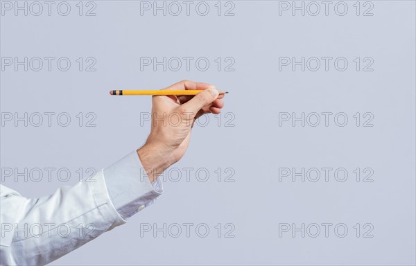 Male hand holding a pencil on a blank. Man fingers holding a pencil with blank space. Person hands holding a pencil on a space for text