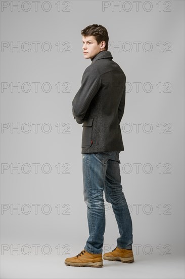 Full length portrait of handsome man in warm woolen coat posing in studio