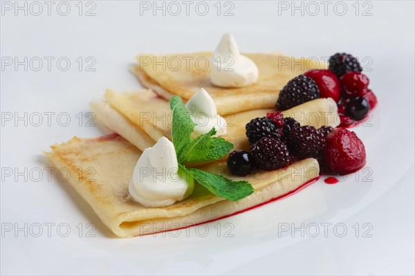 Portion on thin pancakes with sweet cream cheese and berries