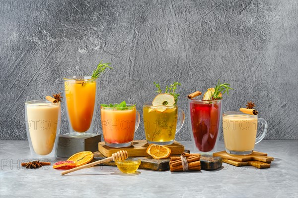 Composition with hot fruit and herbal winter drinks on shabby grey background