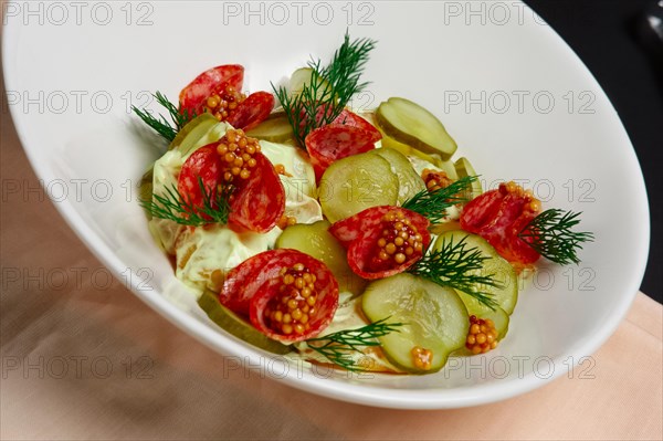 Plate with cucumber and cabbage salad with sausage and whole grain french mustard