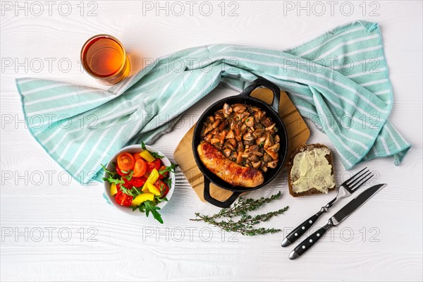 Cast-iron pan with fried sausage and mushrooms