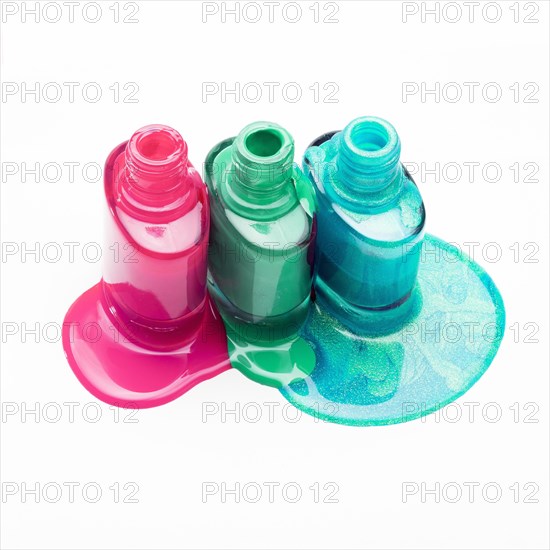 Open bottles with spilled nail polish isolated white surface