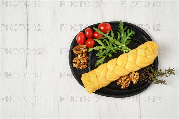 Smoked braided cheese with walnuts and tomatoes on a plate