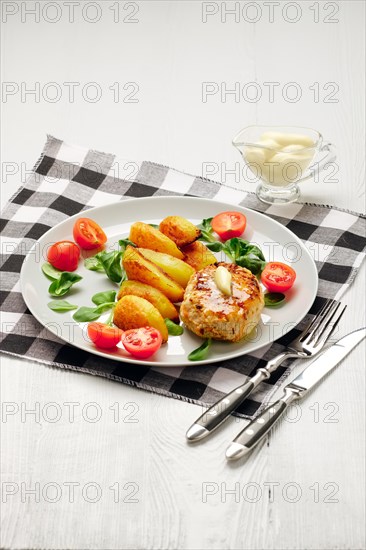 Fried chicken cutlet with potato slices served with tomato cherry and corn salad. Traditional belorussian food