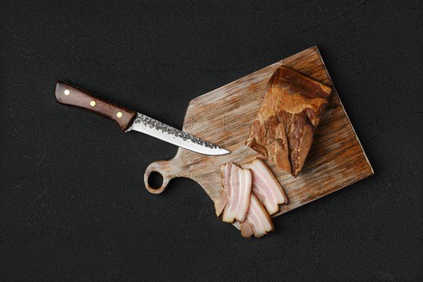 Overhead view of smoked pork bacon with brown bread and eggs on wooden cutting board