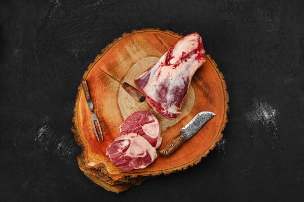 Chopping ossobuco steak from beef shank with cleaver on wooden stump