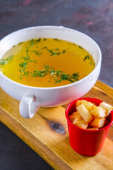 Plate with clear soup and pieces of white bread crouton