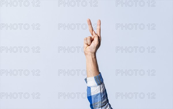 Hand gesturing the letter K in sign language on an isolated background. Man's hand gesturing the letter K of the alphabet isolated. Letters of the alphabet in sign language