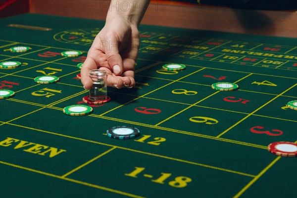 Casino roulette table with chips and cards. Winning combination. Hand of Croupier behind gambling table