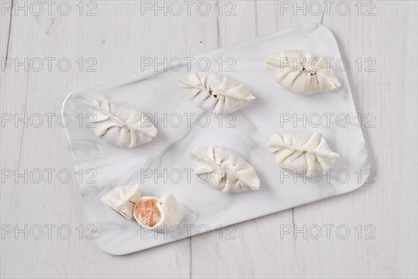 Top view of frozen dumplings stuffed with liver and provencal herbs on marble serving plate