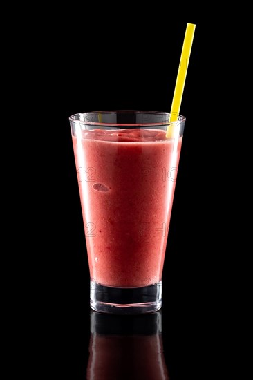 Glass of fresh cold smoothies with straw isolated on black background
